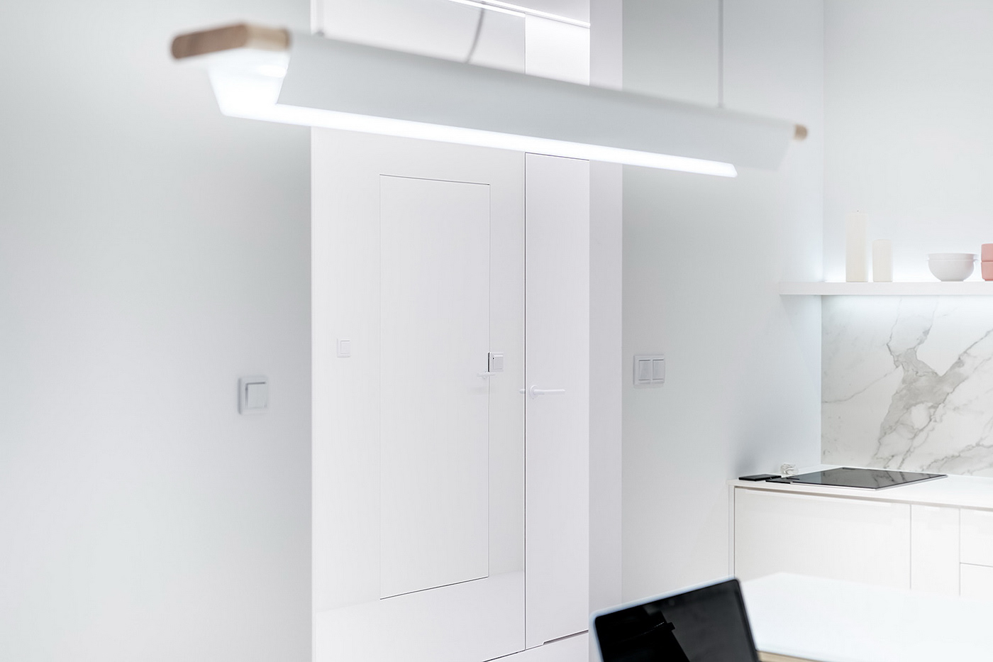 Projekt wnętrza mieszkania 62m2 w Warszawie - biała kuchnia z liniową lampą i zabudową meblową