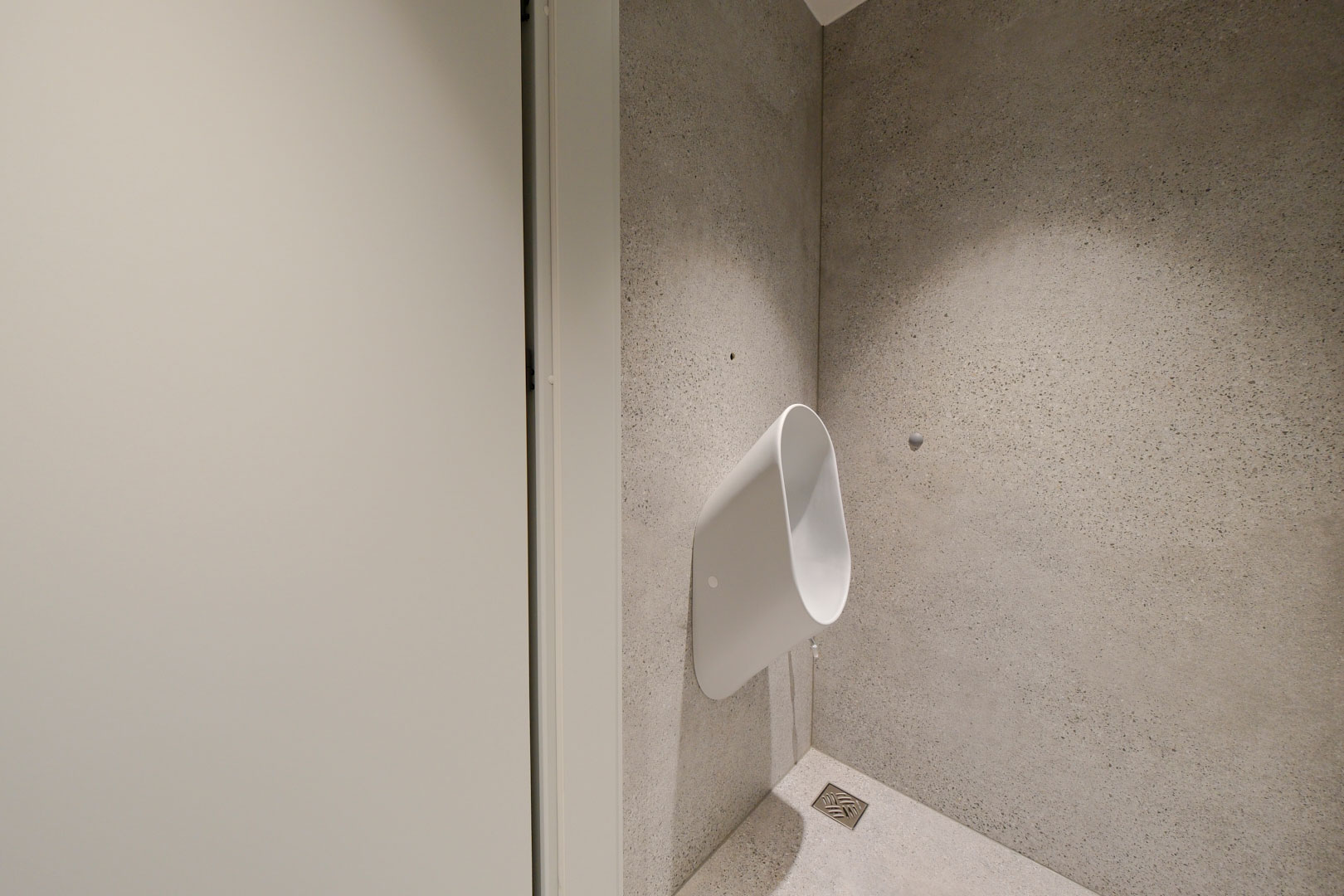Toaleta męska w projekcie wnętrza biurowego z minimalistycznym pisuarem